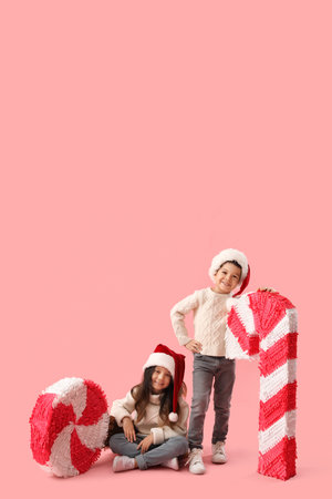 Cute little children with Christmas pinatas on pink backgroundの写真素材