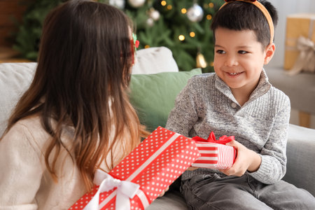 Cute little children exchanging Christmas gifts at homeの写真素材
