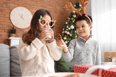 Cute little children with glass of milk and cookies on Christmas Eve at homeの写真素材