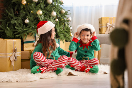 Adorable little children in elf's costumes on Christmas Eve at homeの写真素材
