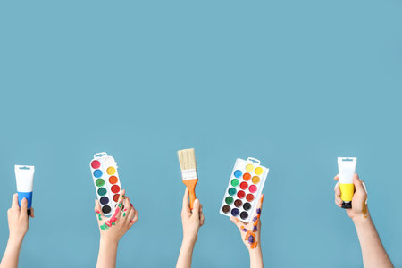 Female hands with artist's supplies on blue background