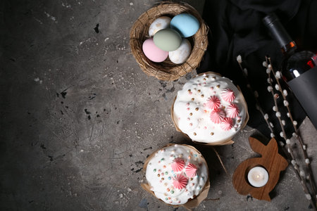 Easter cakes, painted eggs in nest, candlestick in shape of rabbit and willow branches on grunge...