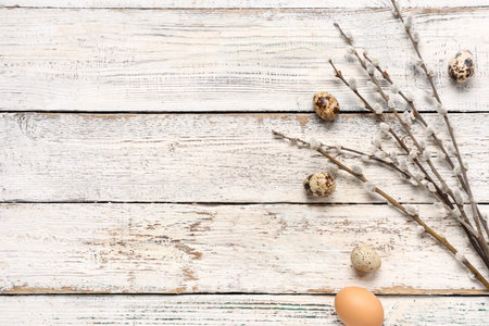Pussy willow branches and Easter eggs on white wooden background