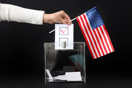 Voting woman with flag of USA near ballot box on black backgroundの写真素材