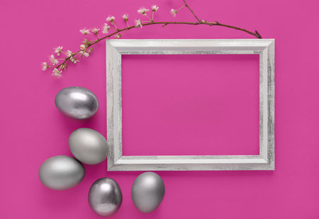 Stylish frame with blossoming branch and silver eggs on pink backgroundの写真素材