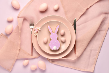 Festive table setting with painted Easter eggs, cookie in shape of bunny and flowers on lilac backgroundの写真素材