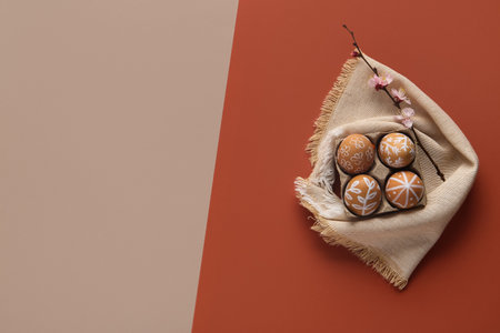 Painted Easter eggs with napkin and blossoming branch on color backgroundの写真素材