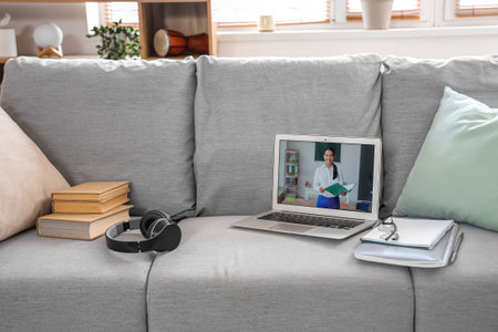 Screen of laptop with teacher giving online lesson on sofa in roomの写真素材