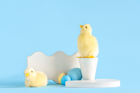 Decorative podiums with chicks and Easter eggs on blue background