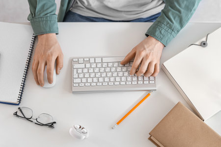 Male student with computer studying online on table, top viewの写真素材