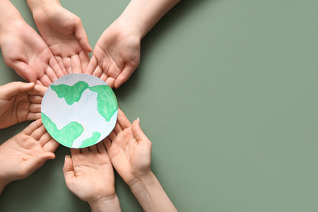 Hands holding paper planet Earth on green background. Earth Day celebration.の写真素材