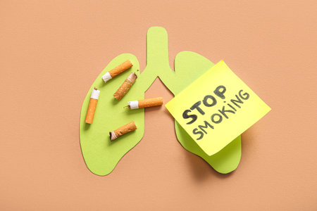 Cigarette butts, sticky note with phrase STOP SMOKING and paper lungs on beige background, closeup. Stop smoking concept.の写真素材