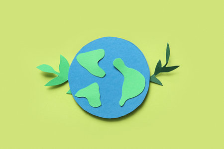 Paper planet Earth with green paper leaves on green background. Earth Day celebration.の写真素材