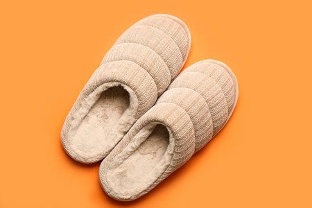 Pair of beige soft slippers on orange background. Top viewの写真素材