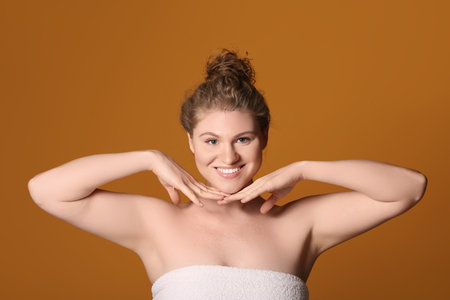 Happy young woman with makeup foundation on her face against brown backgroundの写真素材