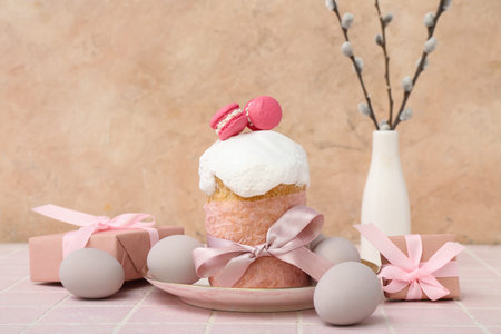 Plate with Easter cake, eggs, sweet macarons and gift boxes on pink tile table