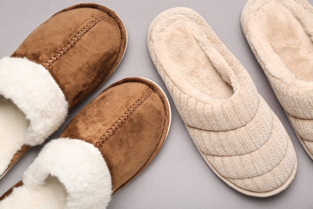 Two pairs of soft slippers on gray background. Top view