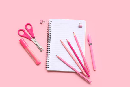 Notebook with pencils on pink background. Top viewの写真素材