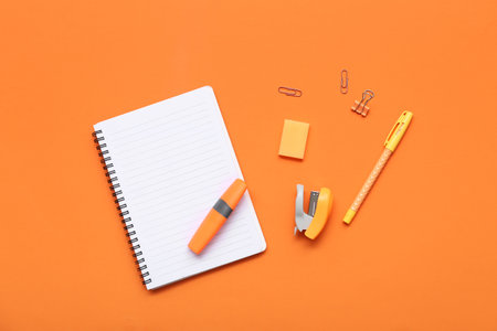 Notebook with stationery on orange background. Top viewの写真素材