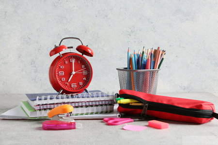 Alarm clock, pencil case and notebooks on table against gray backgroundの写真素材