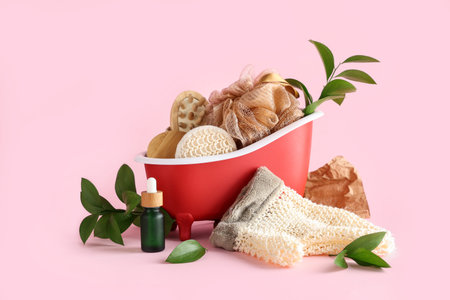 Composition with mini bathtub, spa accessories and plant branches on pink background