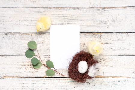 Blank card and toy chickens, nest with Easter egg on white wooden background