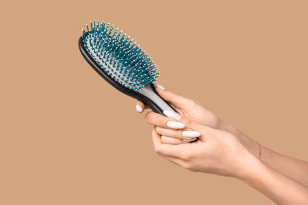 Female hands with hair brush on brown backgroundの写真素材