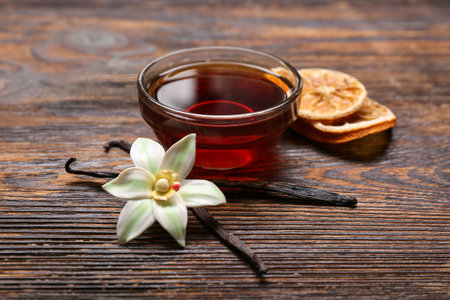Bowl of vanilla extract, sticks and dried orange slices on wooden backgroundの写真素材