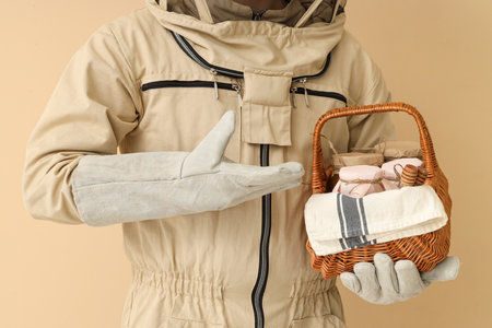 Male beekeeper with basket of honey on beige background, closeupの写真素材