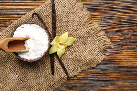 Bowl of vanilla powder, sticks and flower on wooden backgroundの写真素材