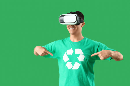 Male ecologist in VR glasses pointing at recycle sign on his t-shirt against green backgroundの写真素材