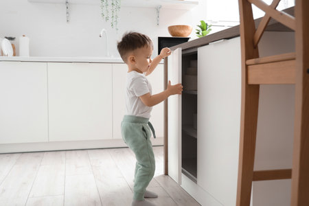 Little boy opening drawer in kitchen. Child at riskの写真素材