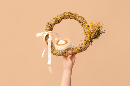 Female hands with Easter festive wreath on beige background