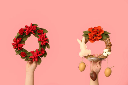 Female hands with Easter festive wreaths on pink background