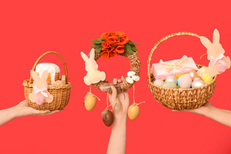 Female hands with Easter festive wreath and baskets on red backgroundの写真素材