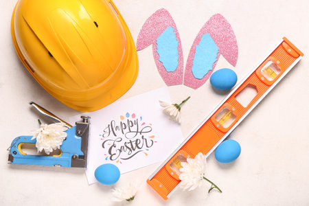 Composition with greeting card, construction tools and Easter decor on light backgroundの写真素材