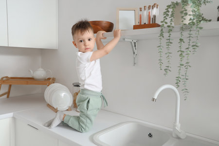 Little boy near high shelf in kitchen. Child at riskの写真素材