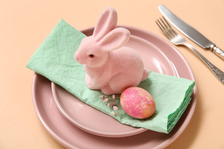 Beautiful table setting with Easter egg, toy bunny and gypsophila flowers on orange backgroundの写真素材