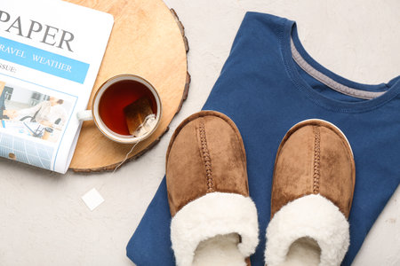Pair of soft brown slippers with cup of tea and newspaper on white background. Top viewの写真素材