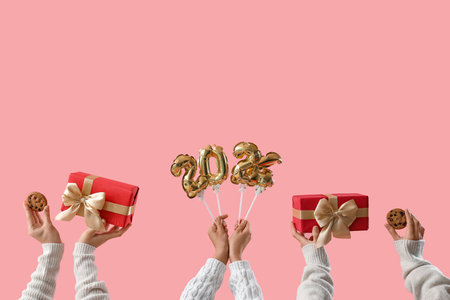 Many hands with Christmas gifts, cookies and balloons in shape of figure 2024 on pink backgroundの写真素材