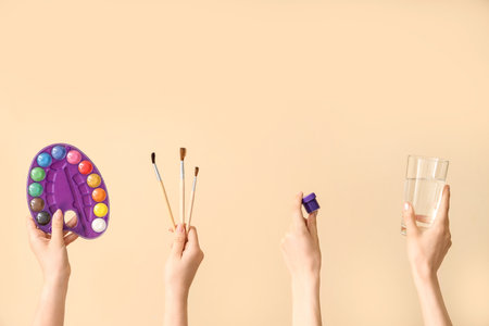 Female hands with artist's supplies on beige backgroundの写真素材