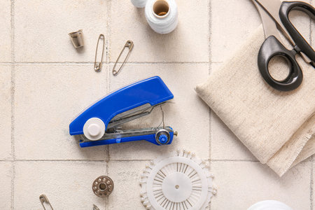 Manual sewing machine with different supplies on white tile background