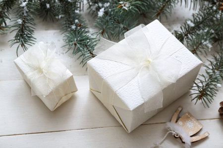Christmas tree branches and gift boxes on white wooden backgroundの写真素材