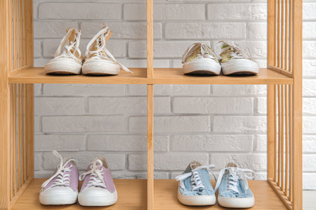 Wooden shelving unit with stylish female shoes near light brick wall, closeupの写真素材