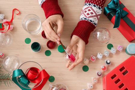 Woman decorating Christmas ball with paints on tableの写真素材
