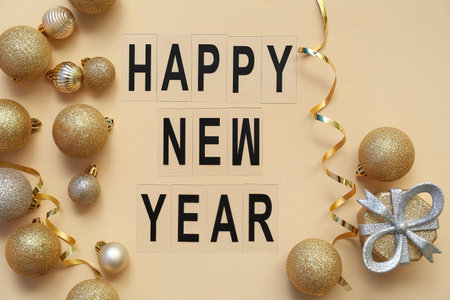 Text HAPPY NEW YEAR with Christmas balls and gift box on yellow backgroundの写真素材