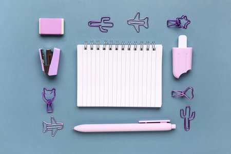 Notebook with different stationery supplies on blue background