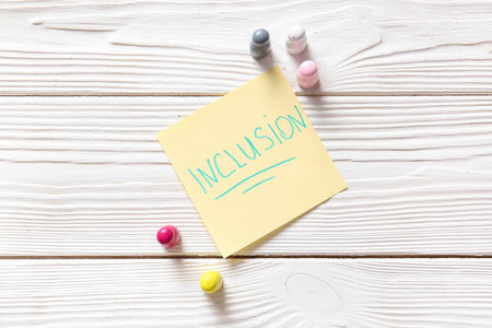 Paper with word INCLUSION and pawns on white wooden backgroundの写真素材