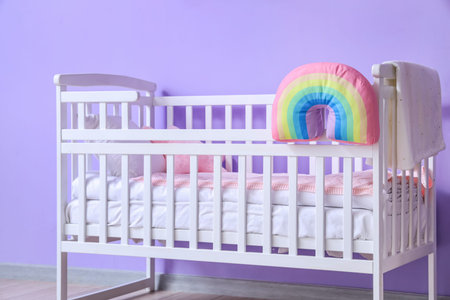 Comfortable baby bed near color wall in room, closeupの写真素材
