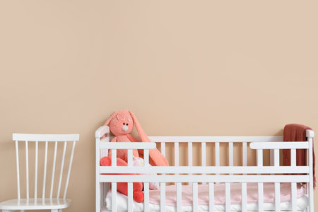 Interior of children's room with crib and toys near beige wallの写真素材